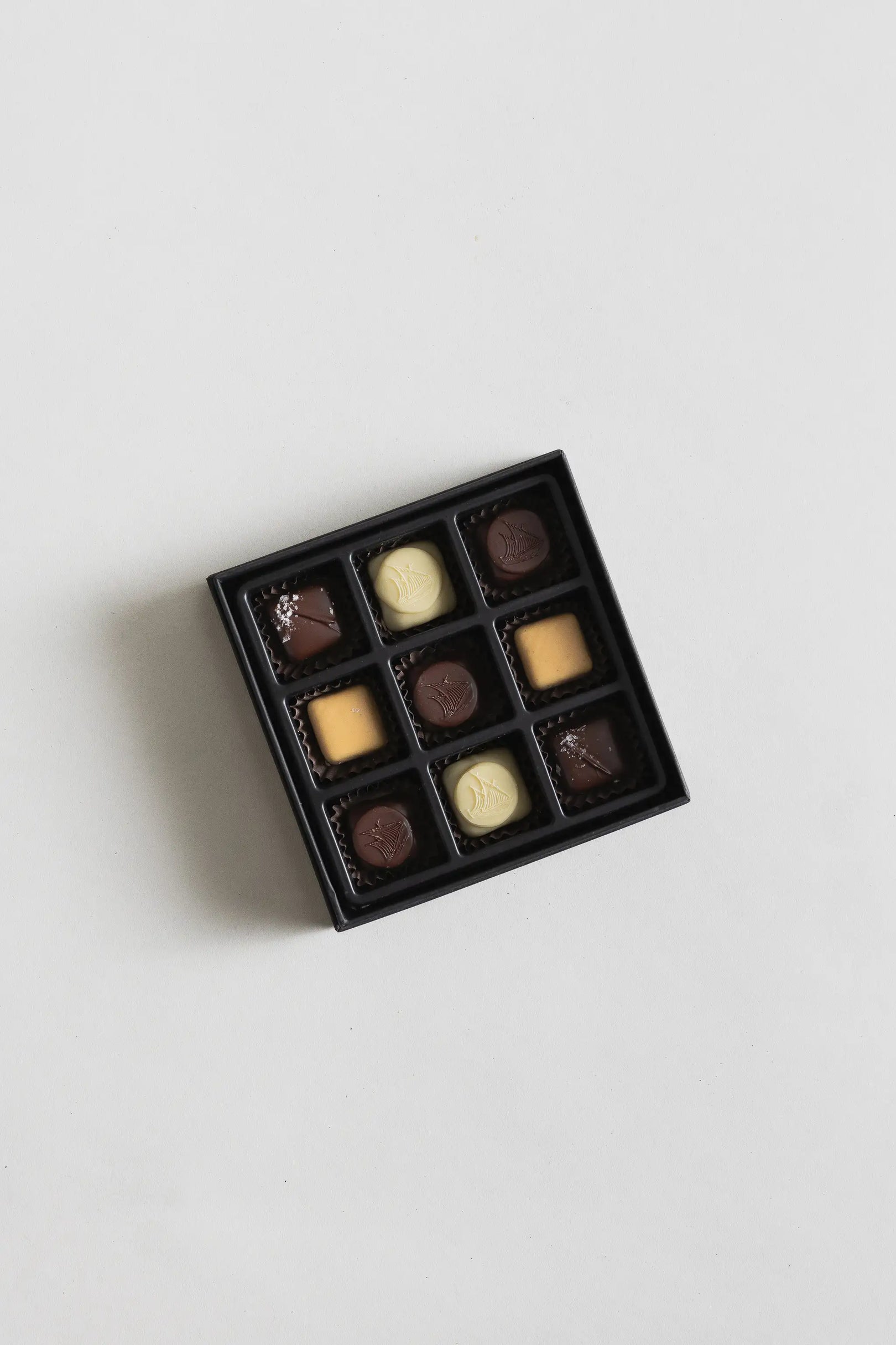 A box of assorted chocolates with dark, milk, and white varieties.