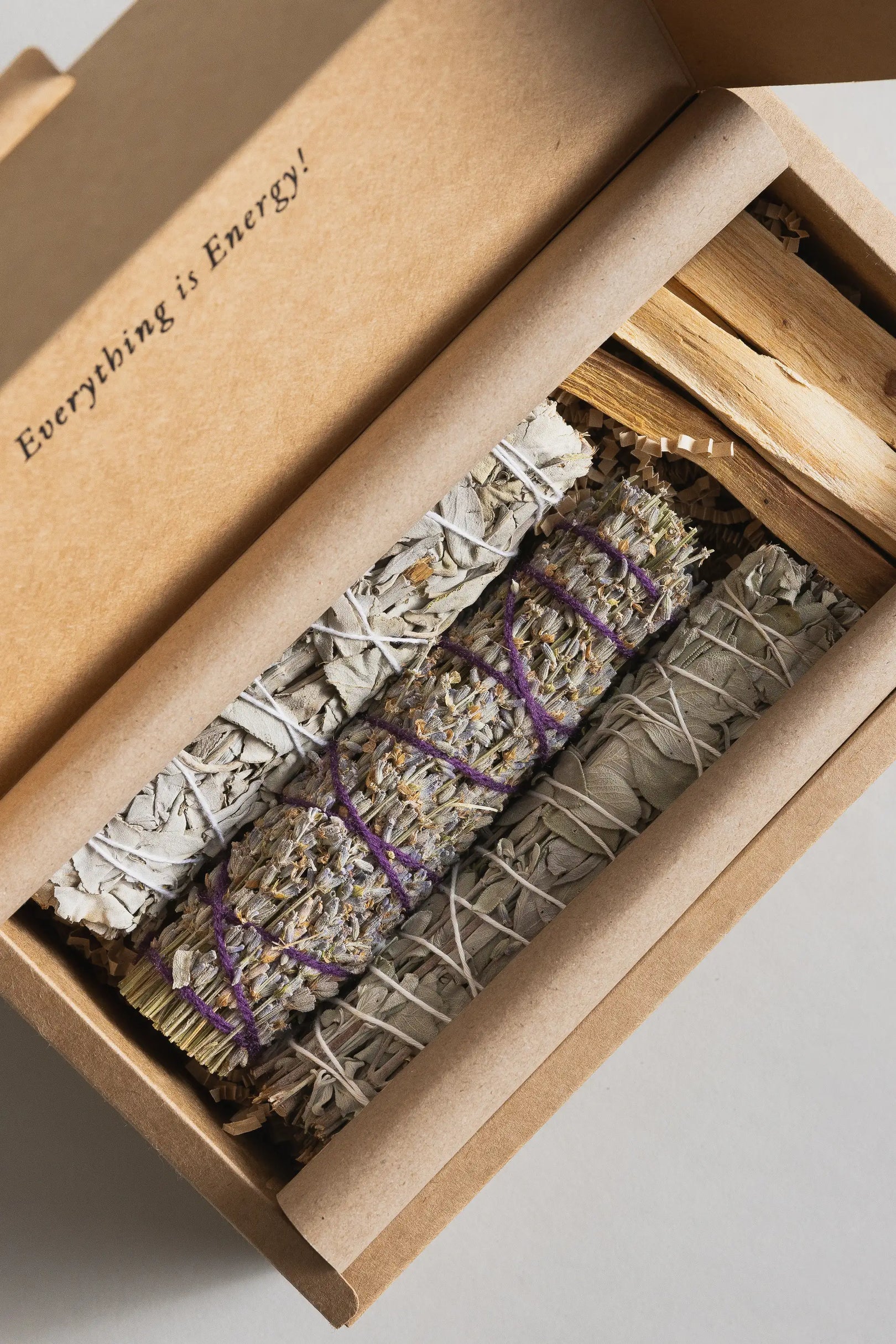 Box containing sage bundles and palo santo wood sticks.